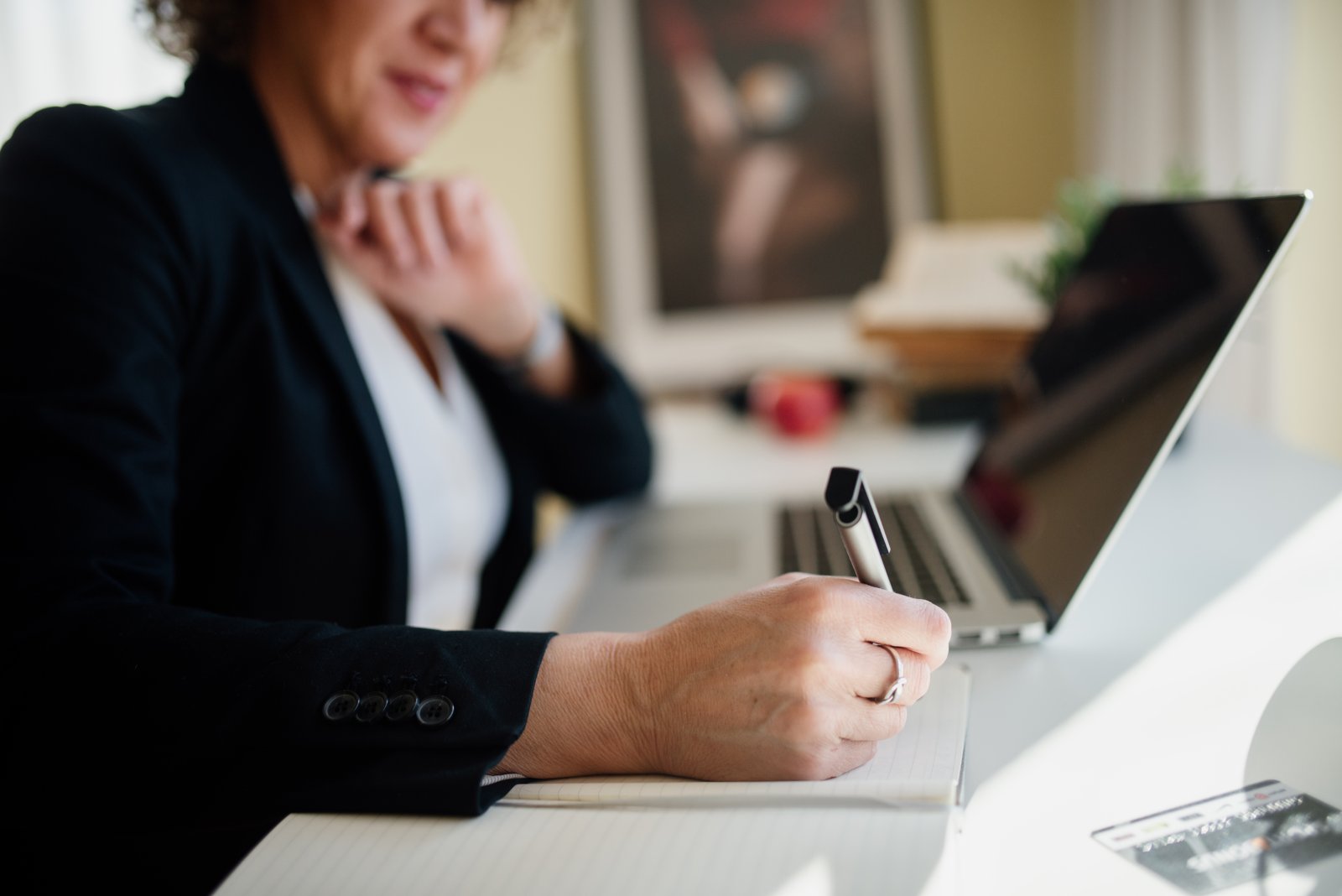 Business professional taking notes during a meeting at a desk