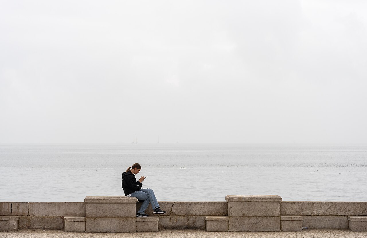 A woman using her smartphone while sitting outdoors
