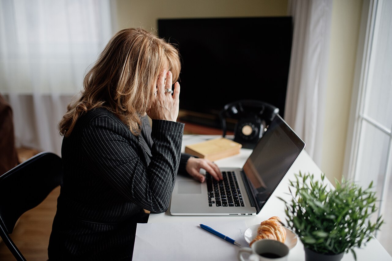 A woman looking tired while working on a laptop at home