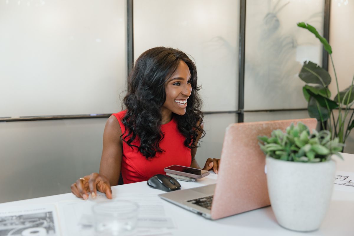 Small business owner reviewing work on a laptop and phone at a desk