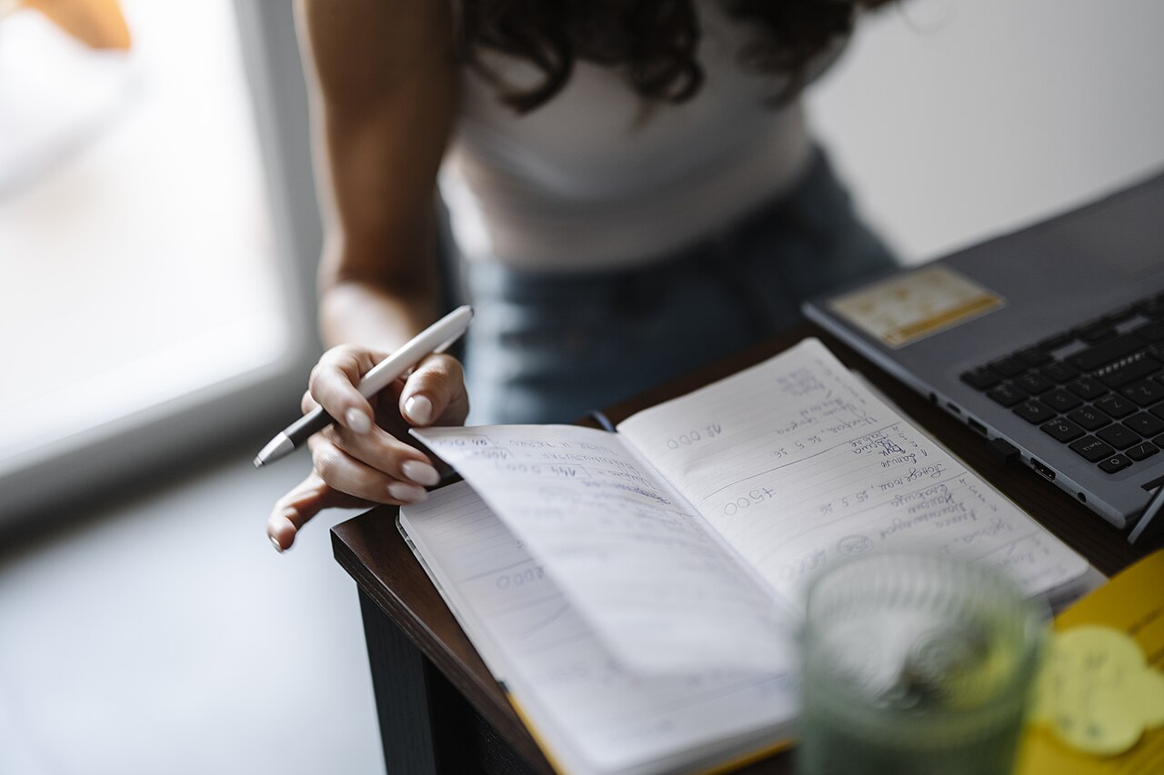 Person writing in a notebook at a desk